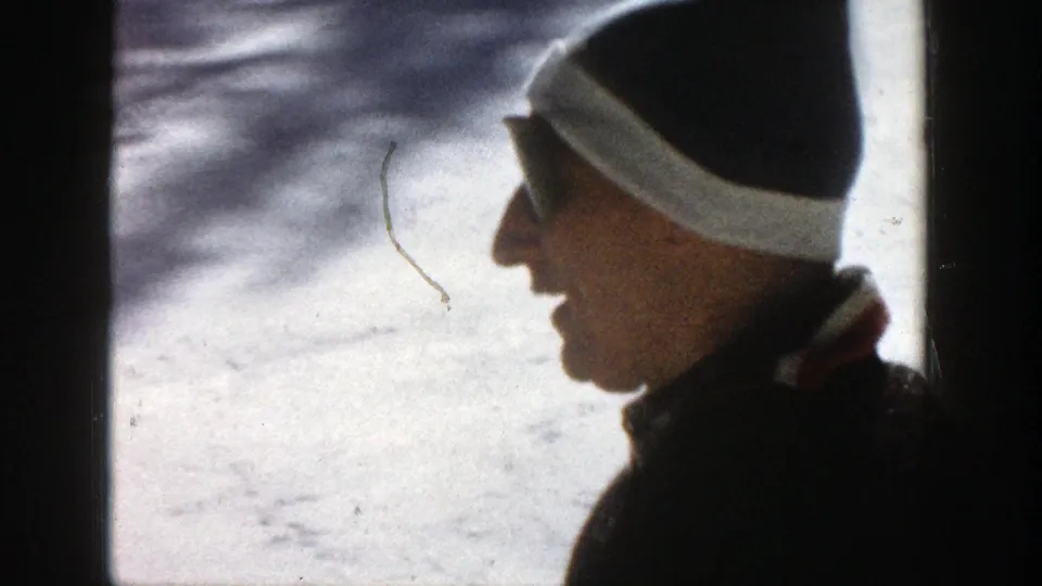 A side profile of a bundled adult man appears against snow in the 1961 Aspen home-movie frame.