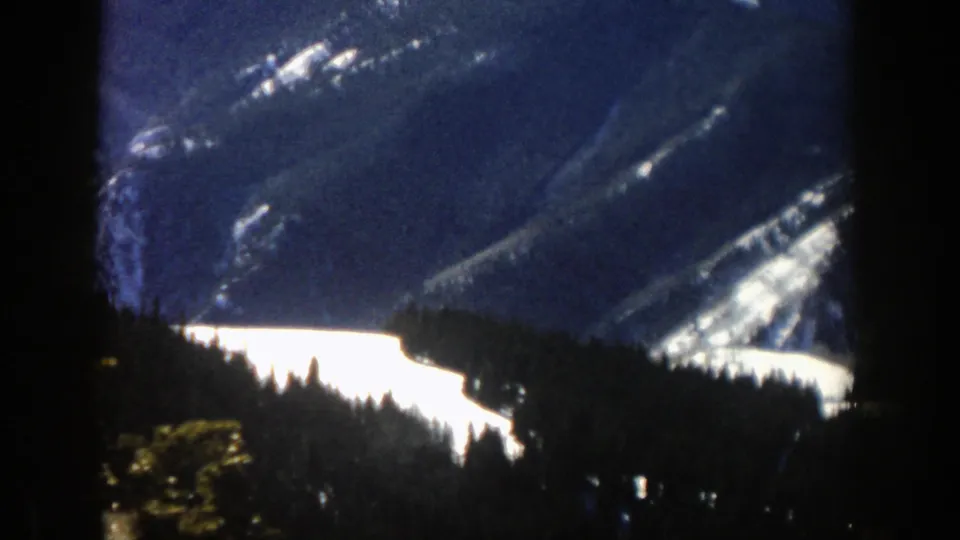 The home-movie view looks across evergreens toward a snowy valley and mountain ridges in the Aspen area.
