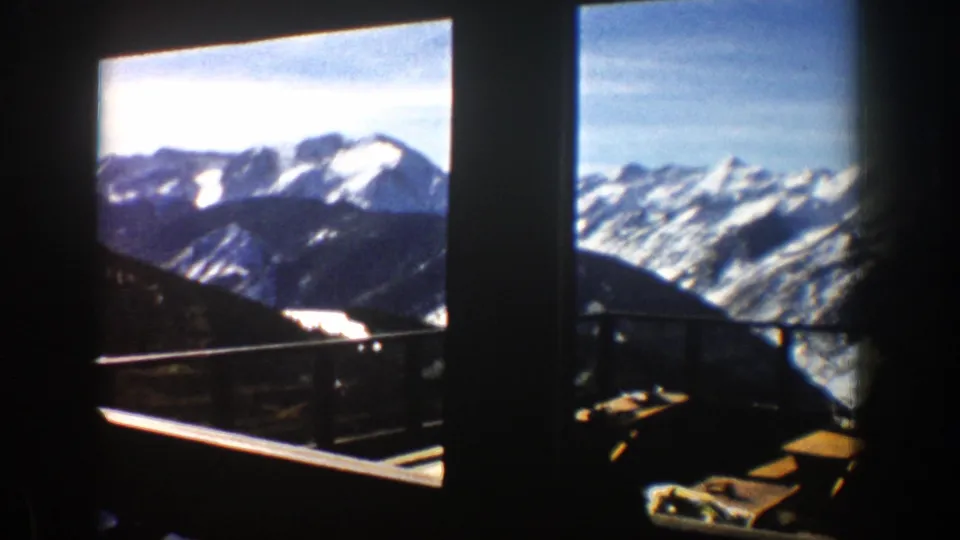 Aspen-area 1961 mountain panorama with snow-covered peaks, blue sky, dark frames, and a visible railing.