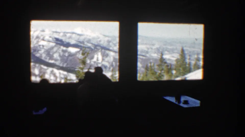 1961 Aspen 8mm frame showing seated silhouettes in a dark interior with snow-covered peaks visible through large windows.