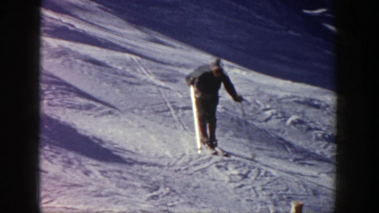Adult skier descends a snowy slope with poles and a dark sweater.