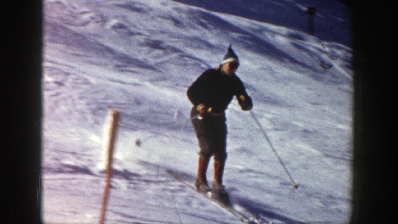 Skier passes a slope marker while moving downhill on snow.