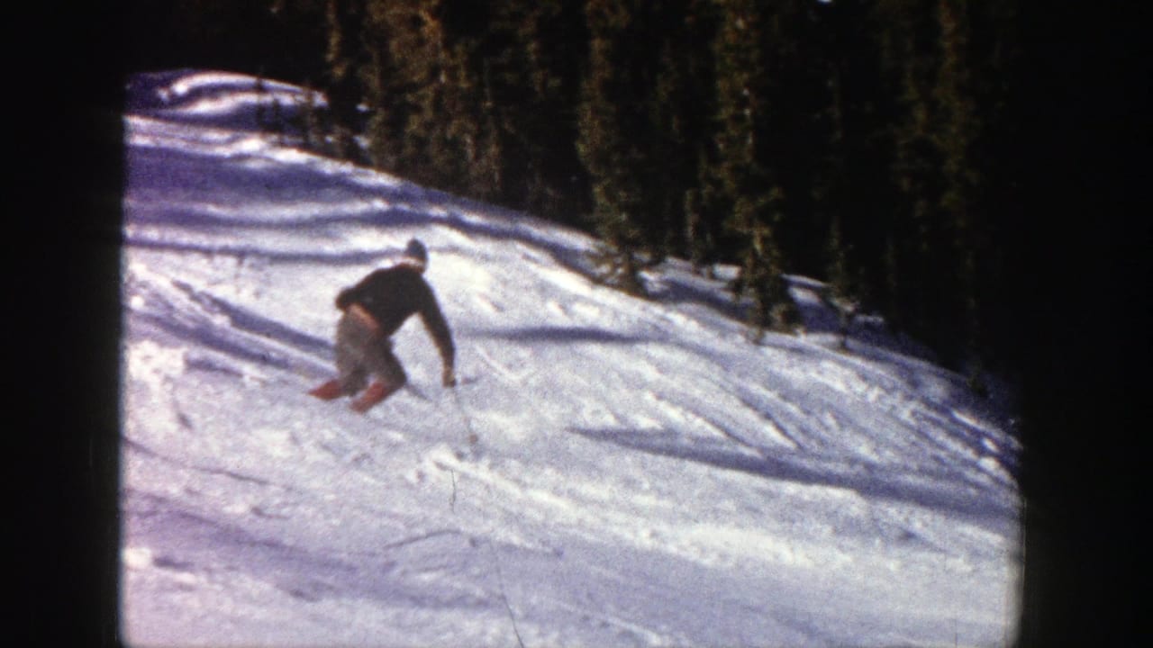 Skier leans into a turn on a bright snowy hillside.