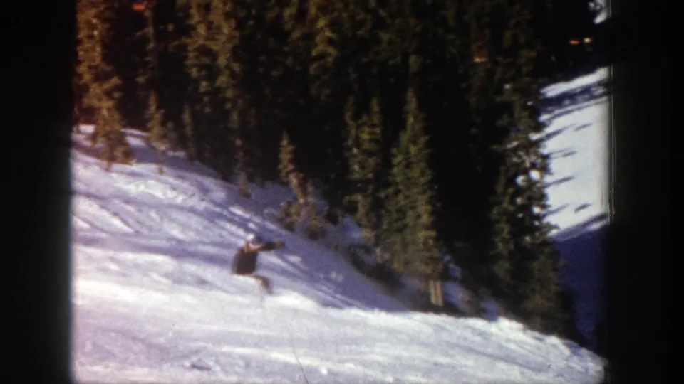 Near the end of the clip, the skier is smaller in frame on the Aspen slope, with evergreen trees bordering the snowfield.