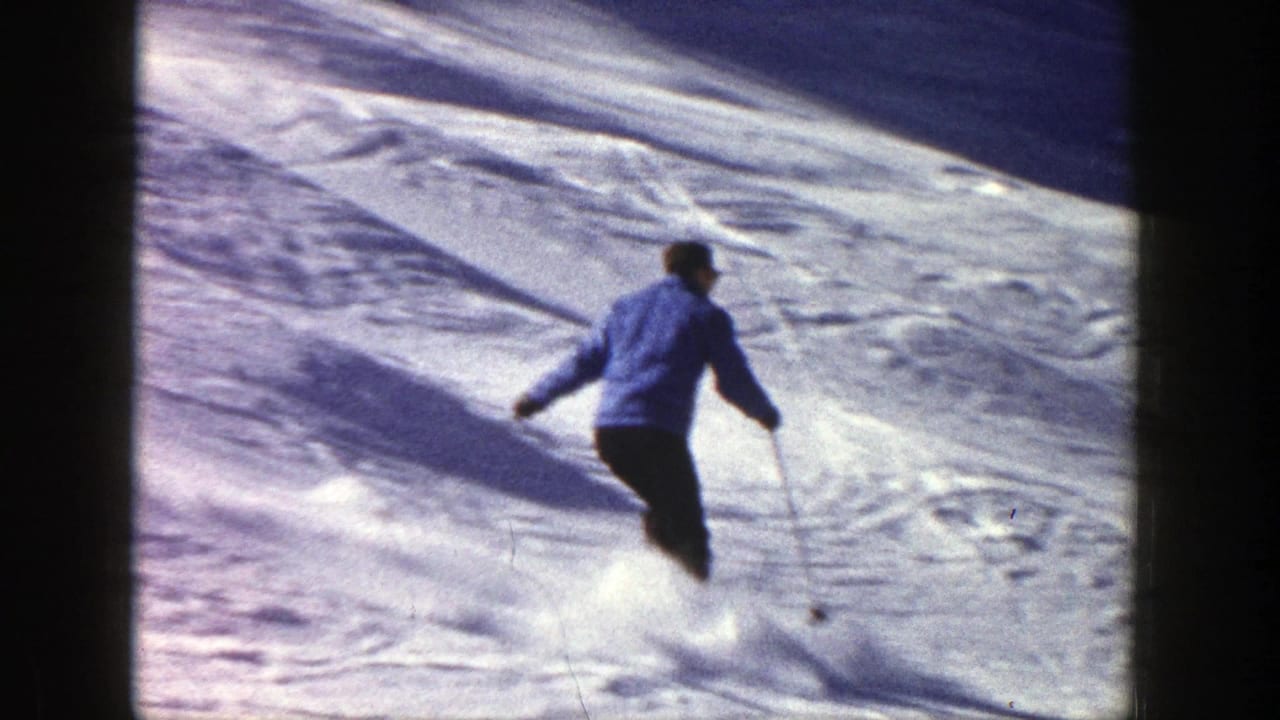 Skier turns across packed snow with poles extended behind them.
