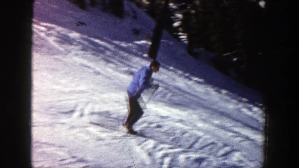 The skier moves along the lower part of the Aspen slope, with dark tree shadows bordering the bright snow.