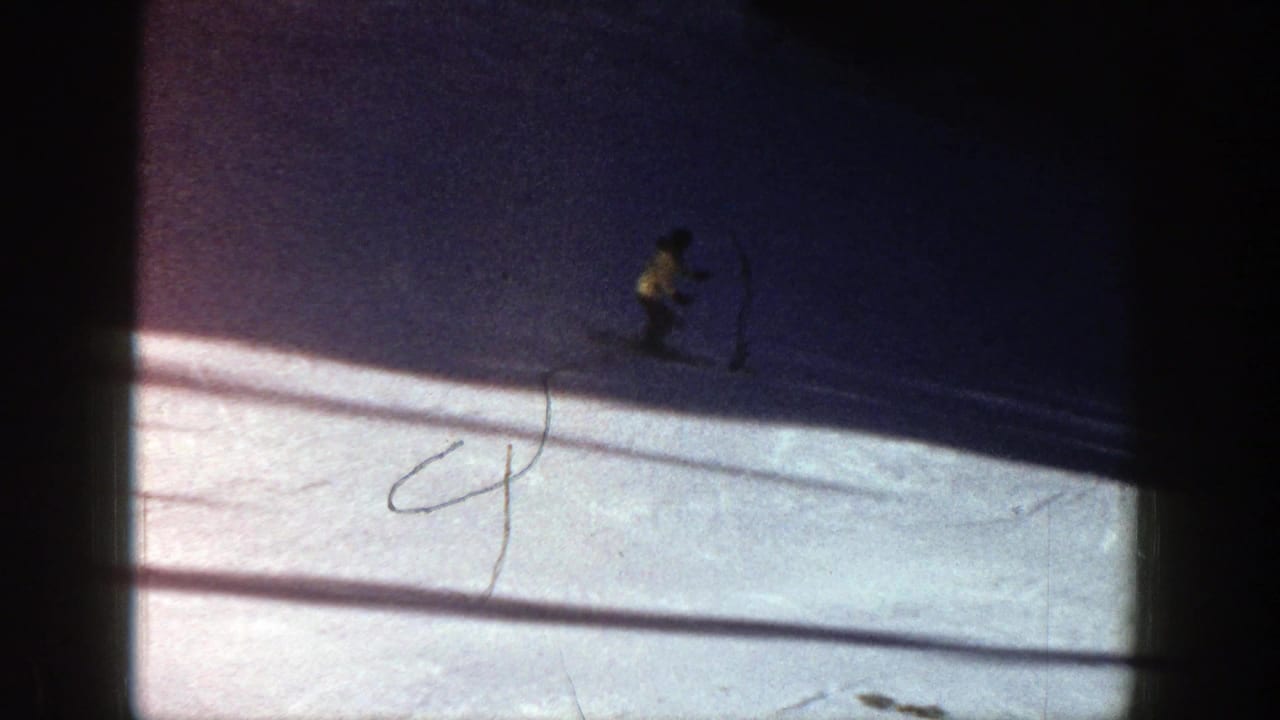 Small skier near the upper right moves through shadowed snow.