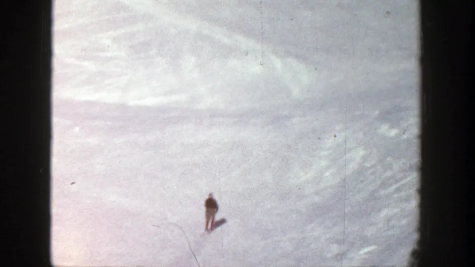 The skier is very small in the lower part of the Aspen snowfield, emphasizing the scale of the open winter slope.