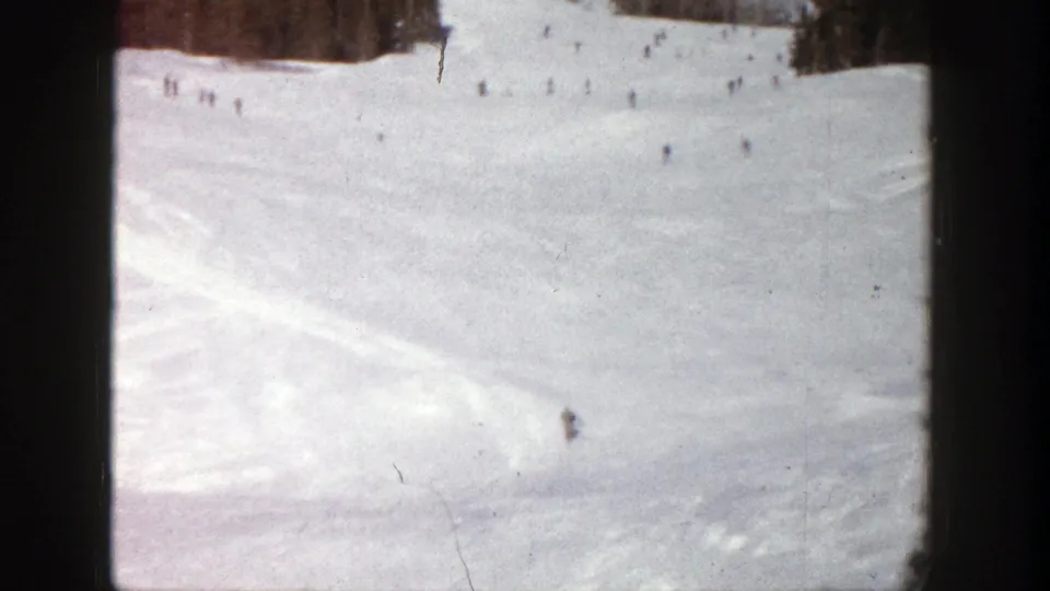 A lone skier remains visible on the lower slope while other small figures dot the distant Aspen snowfield.