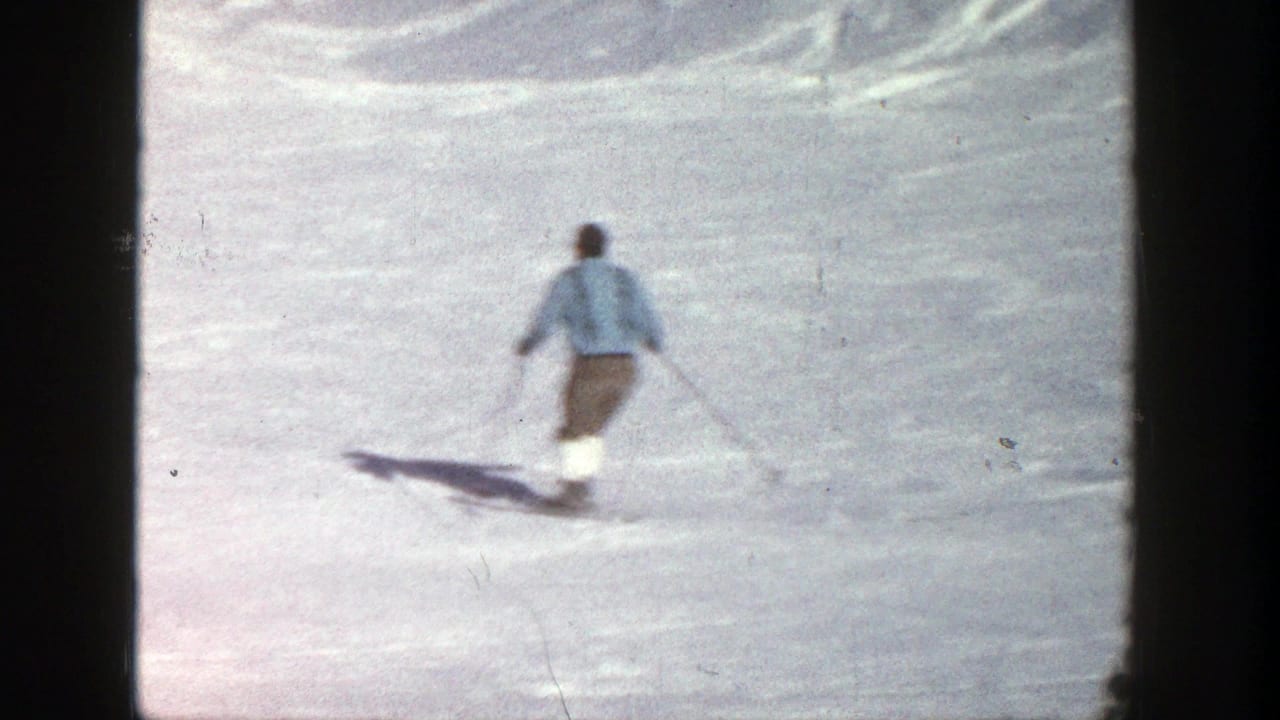 Single skier in a light blue jacket gliding downhill on snow.