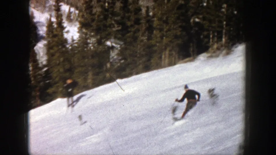 Near the end of the 1961 Aspen clip, one skier descends in the foreground while another figure is visible farther back on the snowy slope.