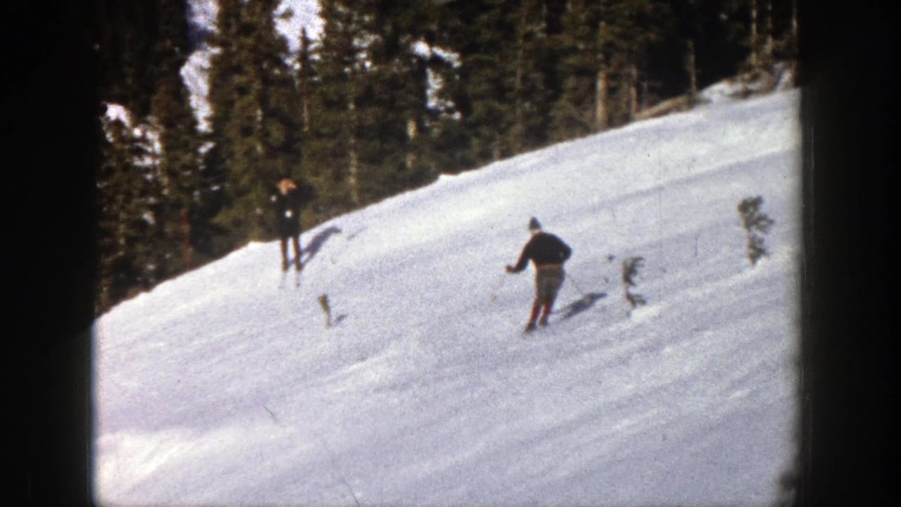 1961 Aspen home-movie frame showing a skier on a bright snowy slope below dark evergreen forest.