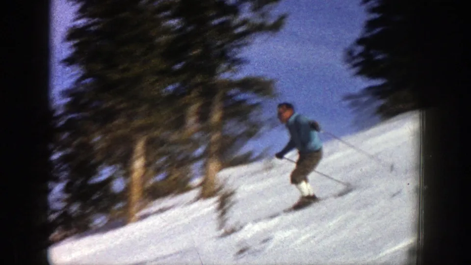 The skier descends a sunlit Aspen slope in 1961, holding poles as evergreen trees blur behind him.