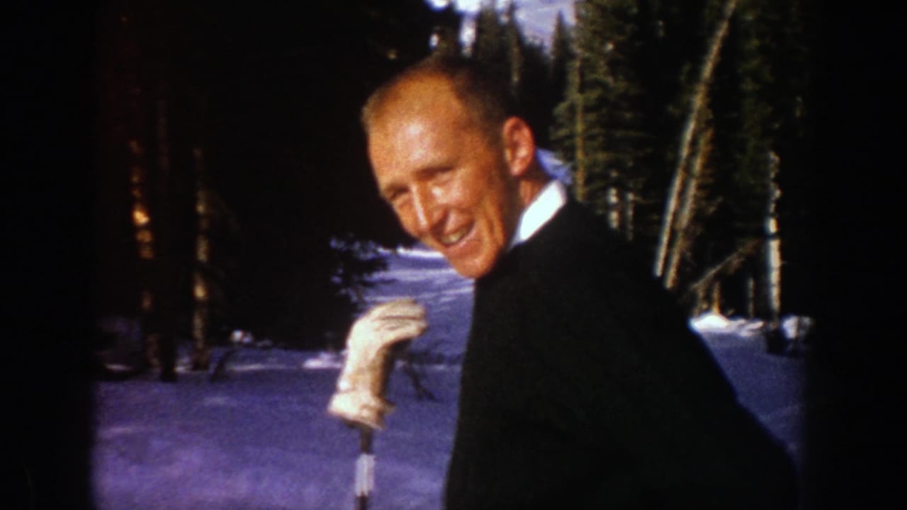 Middle-aged man laughing in snowy Aspen, Colorado, with evergreens behind him in 1961 8mm footage.