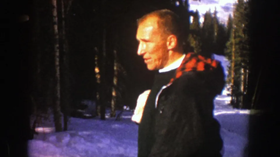Side view of the man in snowy Aspen, showing a dark coat with red plaid lining and a white glove.