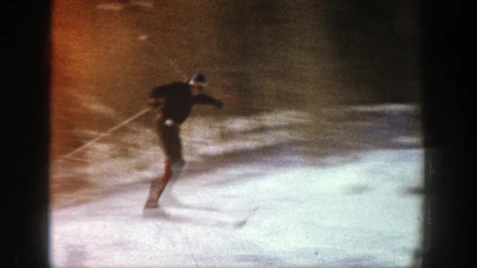 A skier in dark winter clothing crosses a snowy Aspen slope in this 1961 8mm home-movie frame.