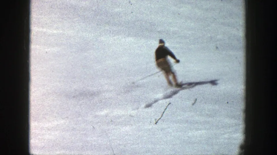 A skier continues downhill across open snow in Aspen, Colorado, with soft 8mm grain and a visible shadow.