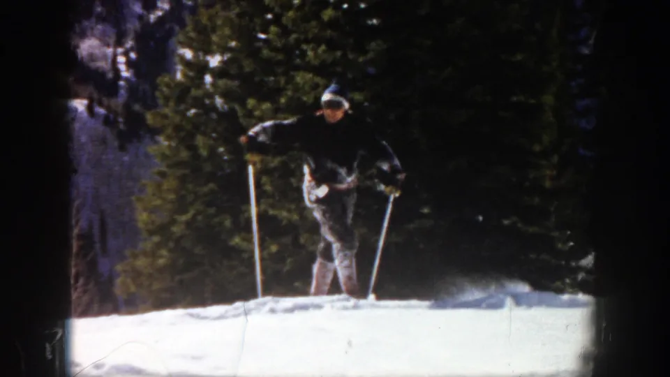 In Aspen, Colorado, a skier in dark clothing and a knit hat practices on a bright snowy slope in 1961 home-movie footage.