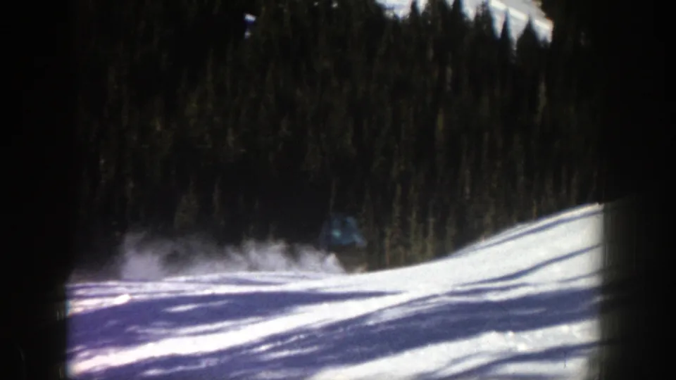 Near the end of the Aspen home-movie shot, the skier is mostly out of view while powder hangs over the snow below the evergreen trees.