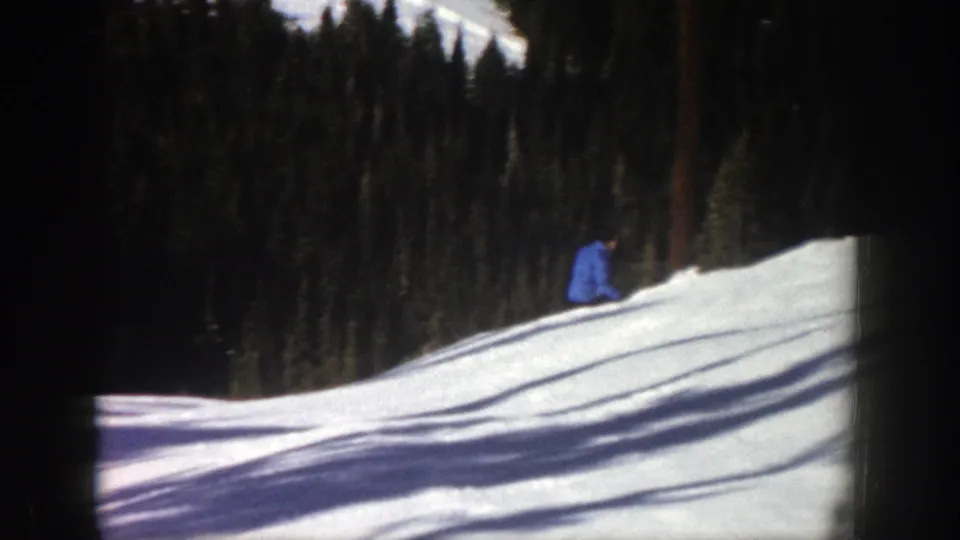 The blue-jacketed skier appears lower on the rolling Aspen slope, partly set against shadowed trees.