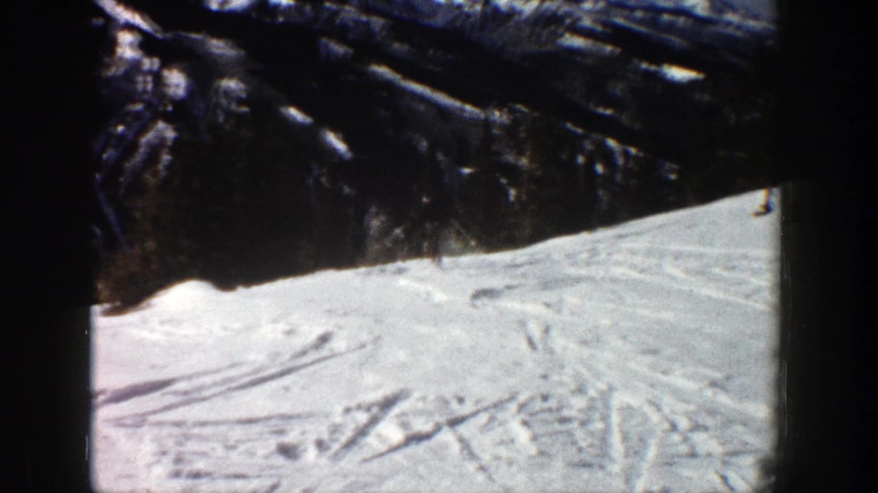 Aspen, Colorado 1961 home-movie frame showing a sunlit ski slope with tracks and dark trees above.