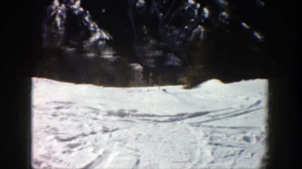 Aspen, Colorado 1961 frame with a tracked ski slope and shadowed wooded edge in vintage 8mm color.