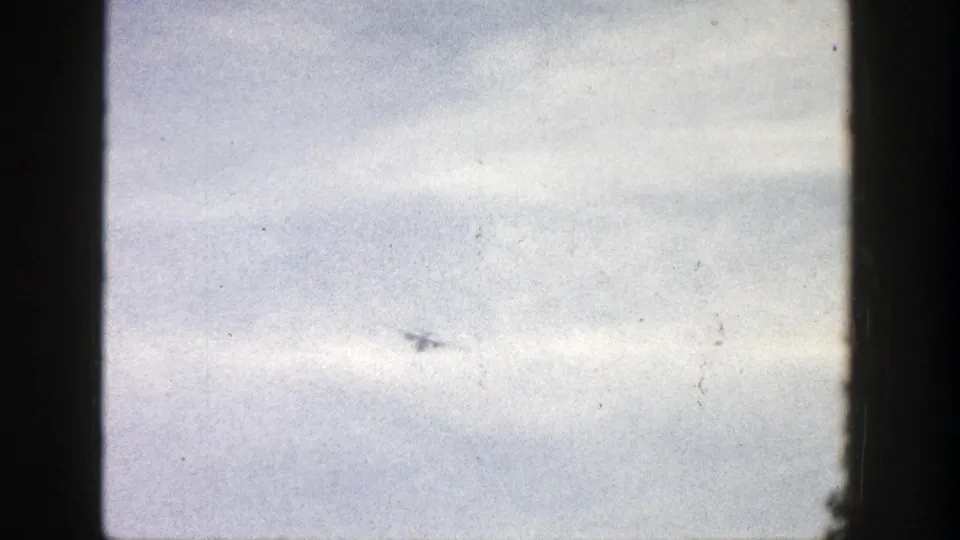 1961 Aspen home-movie frame showing the aircraft farther away near the lower sky area.