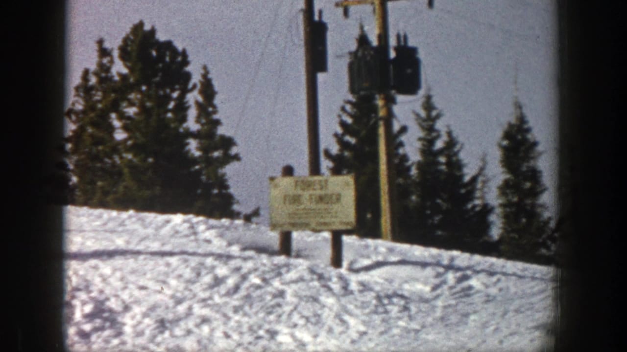 Snowy ski slope with evergreen trees, utility poles, and a Forest Fire Finder sign.