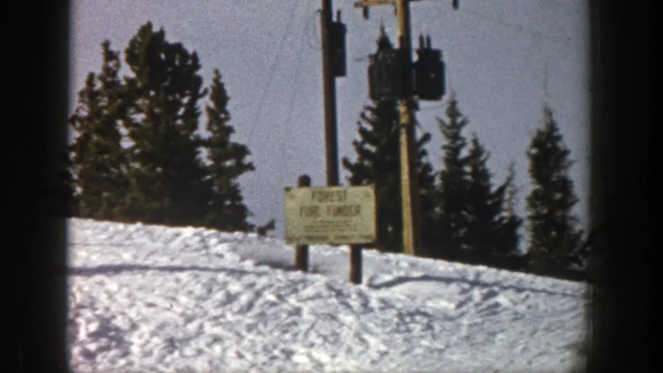 1961 Aspen ski slope with snow, evergreens, utility equipment, and a visible Forest Fire Finder sign near the run.
