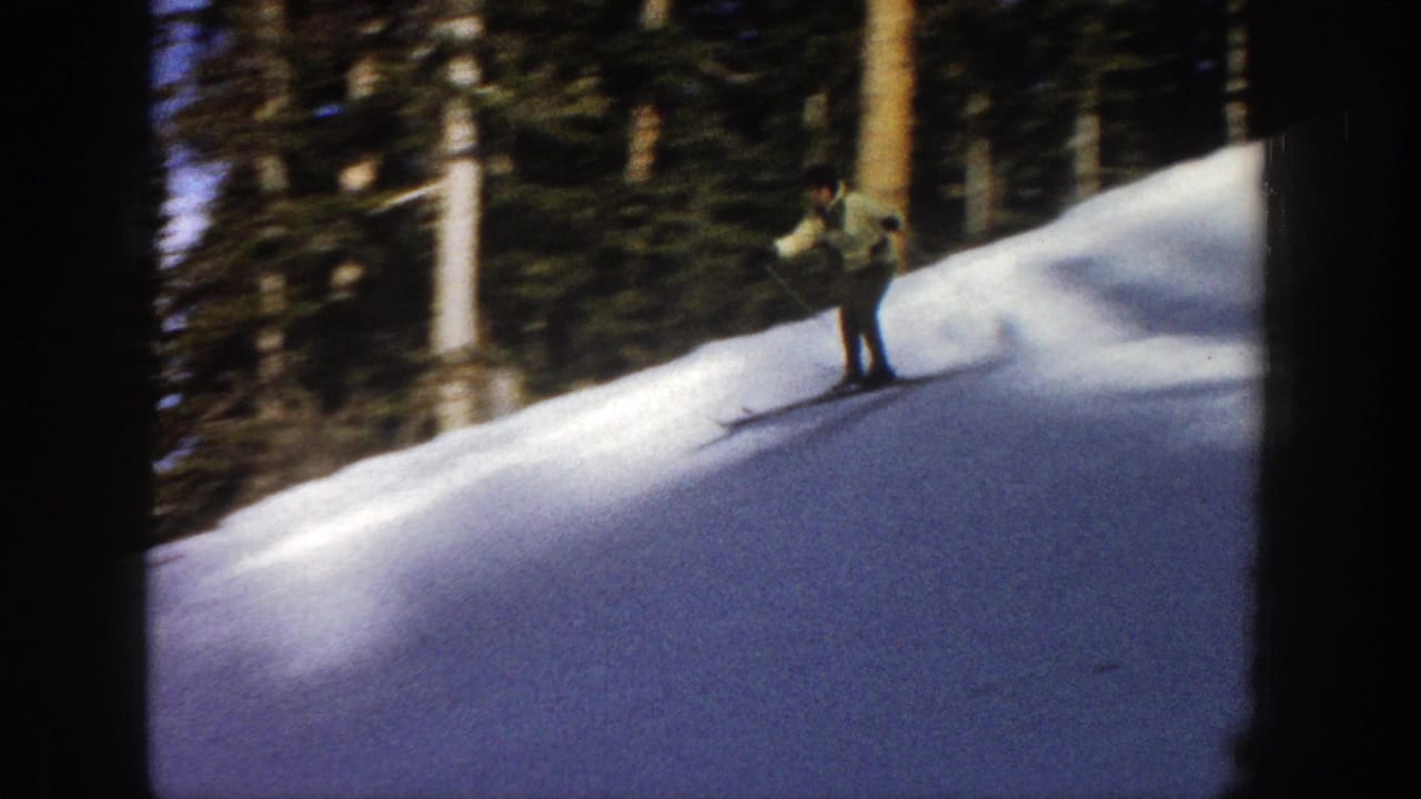 Skier in a light jacket descends a snowy slope near evergreen trees.