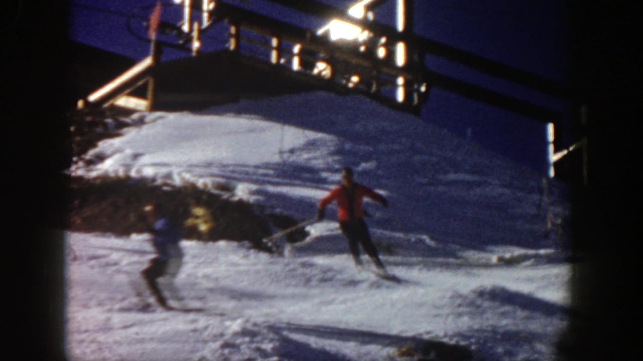 Two skiers pass each other on a snowy slope beneath a raised wooden structure.