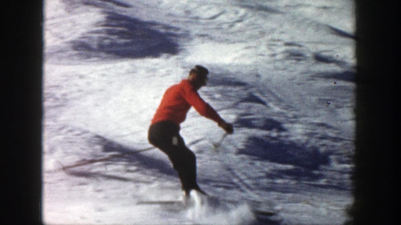 Adult skier in a red jacket makes a downhill turn on a snowy Aspen slope in 1961 home-movie footage.