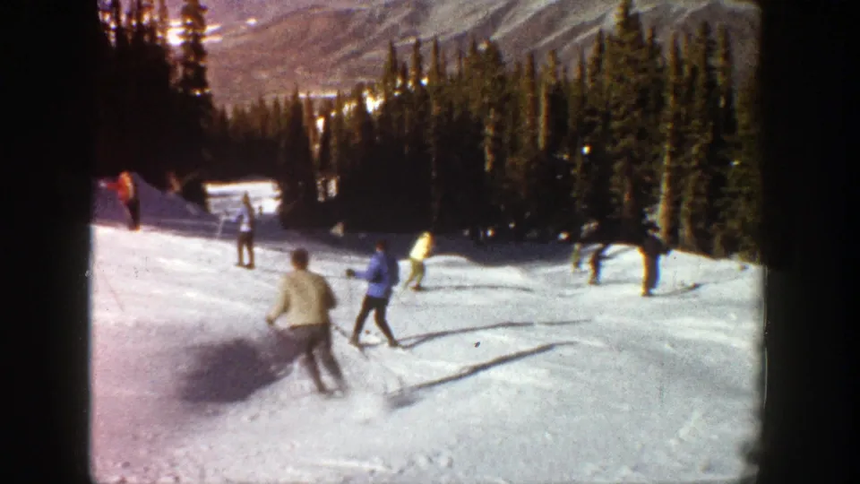 1961 Aspen skiing scene with a skier turning in the foreground and several others spread across the snowy slope.