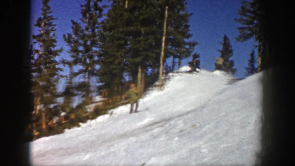 A sunlit Aspen ski slope in 1961 appears mostly empty, with evergreens lining the snowy rise under a clear blue sky.