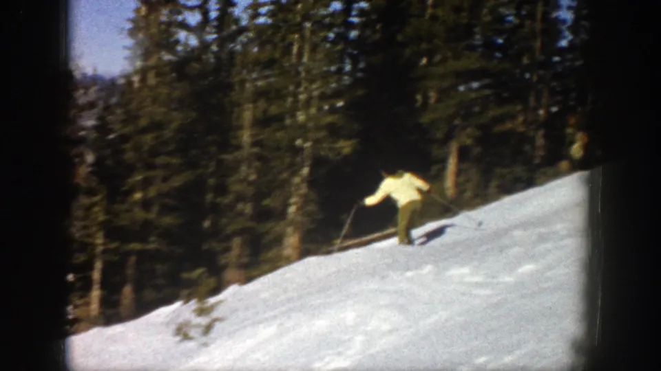 An adult skier descends near the edge of a wooded snow slope in Aspen, Colorado, circa 1961.