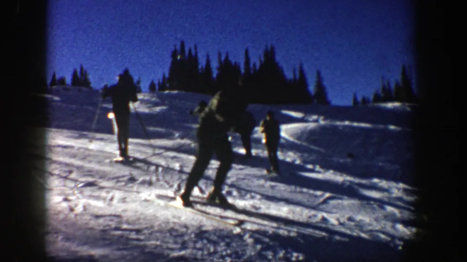 1961 Aspen frame with a foreground skier turning or gliding as other skiers remain on the snowy hillside.