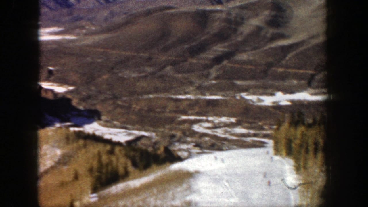 Snowy mountain slope and brown valley seen through dark 8mm frame borders.
