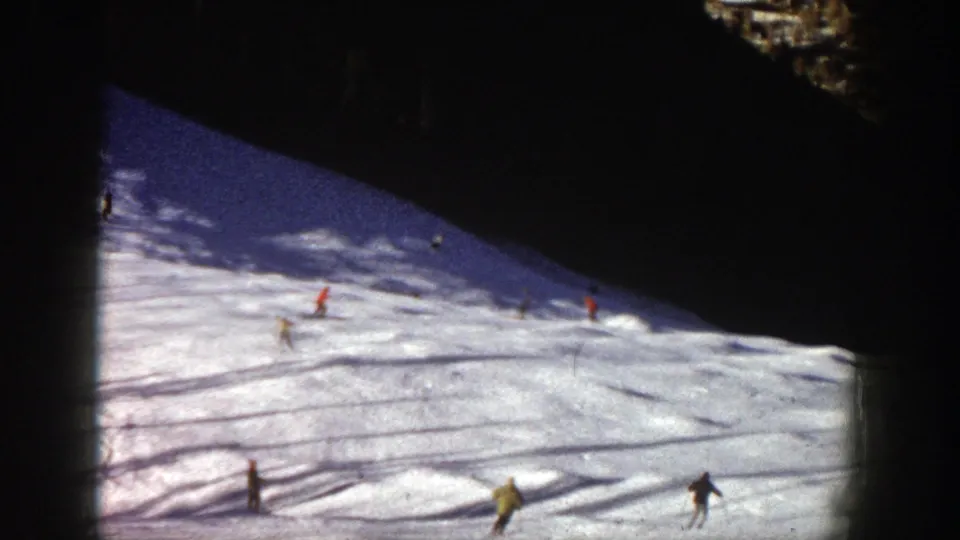 Aspen, Colorado ski run in 1961 with distant skiers crossing bright snow below a shadowed upper slope.