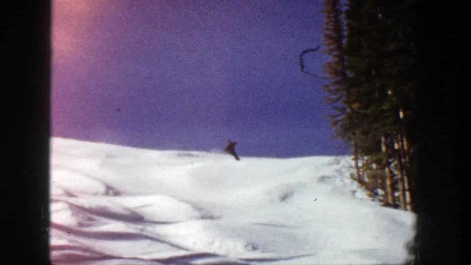 1961 Aspen ski footage frame with a lone skier on a bright slope and evergreen trees along the right side.