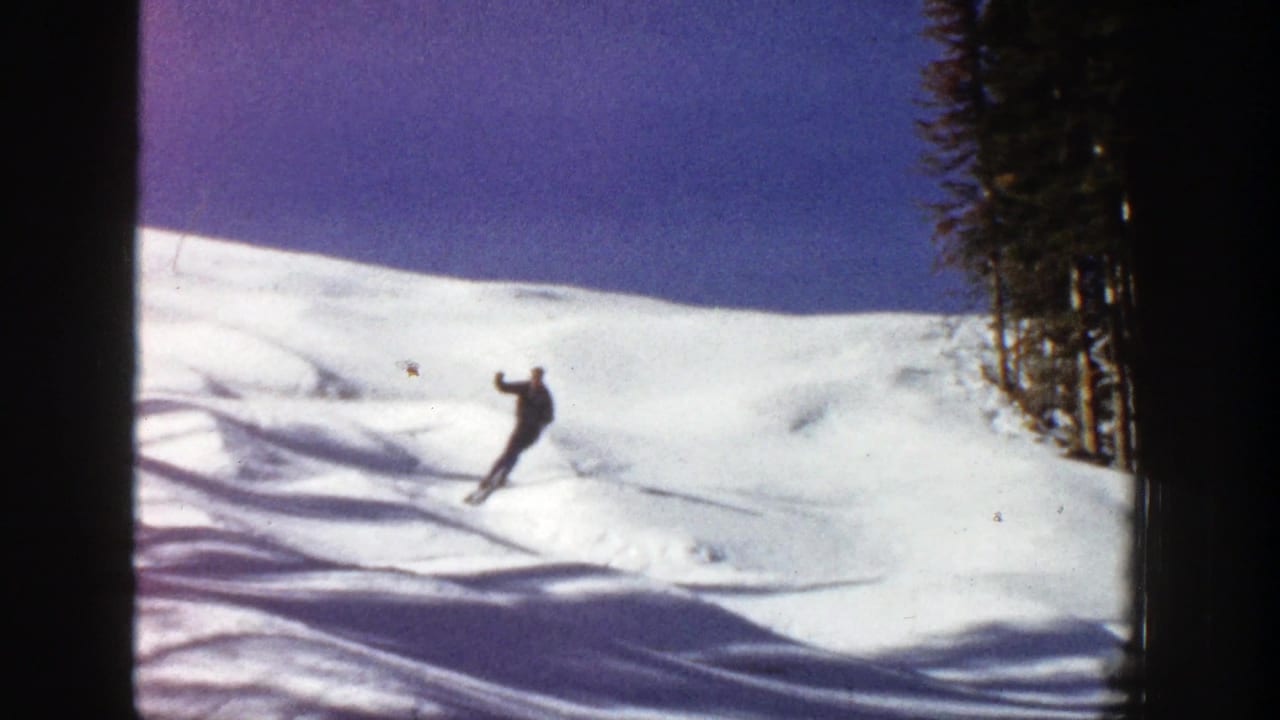 1961 Aspen, Colorado 8mm frame of a skier moving across a bright snow slope with evergreen trees at the right edge.