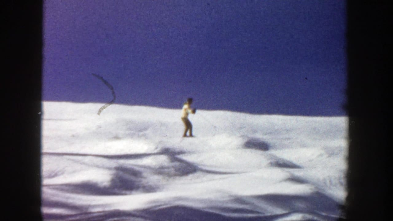 Lone skier on a snowy slope under a deep blue sky.