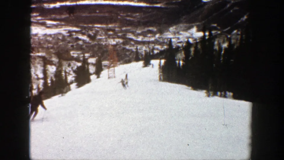 Several skiers move through a tree-lined Aspen slope in a soft, faded 8mm frame from 1961.