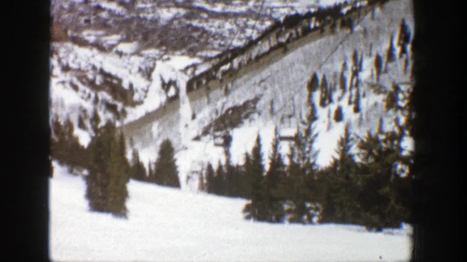 1961 Aspen ski-resort landscape showing snow-covered runs, evergreen clusters, lift towers, and cable lines across the mountain.