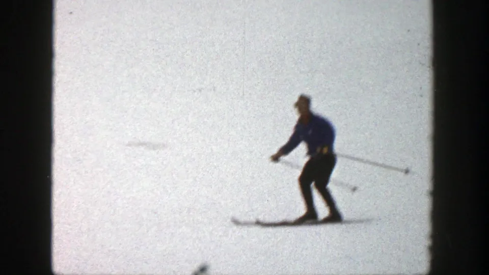 1961 Aspen frame of a skier in a blue jacket moving across an open snowy slope, with soft 8mm focus and grain.