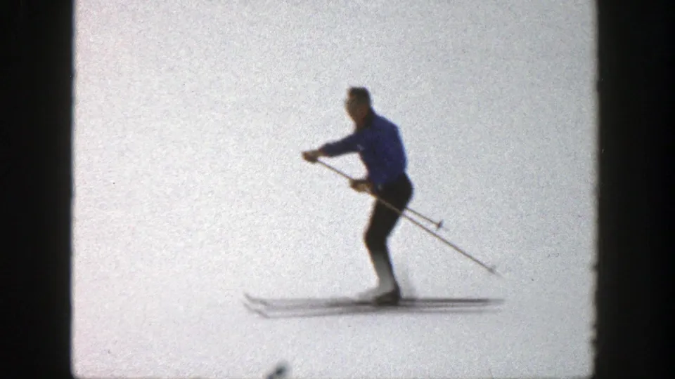 Adult skier in a blue coat and dark pants moves across snow in Aspen, Colorado, 1961 home-movie footage.