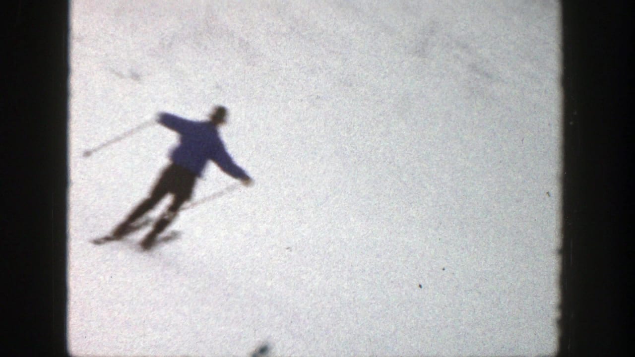 In Aspen, Colorado, 1961 footage, a skier in blue descends across snow while using poles for balance.