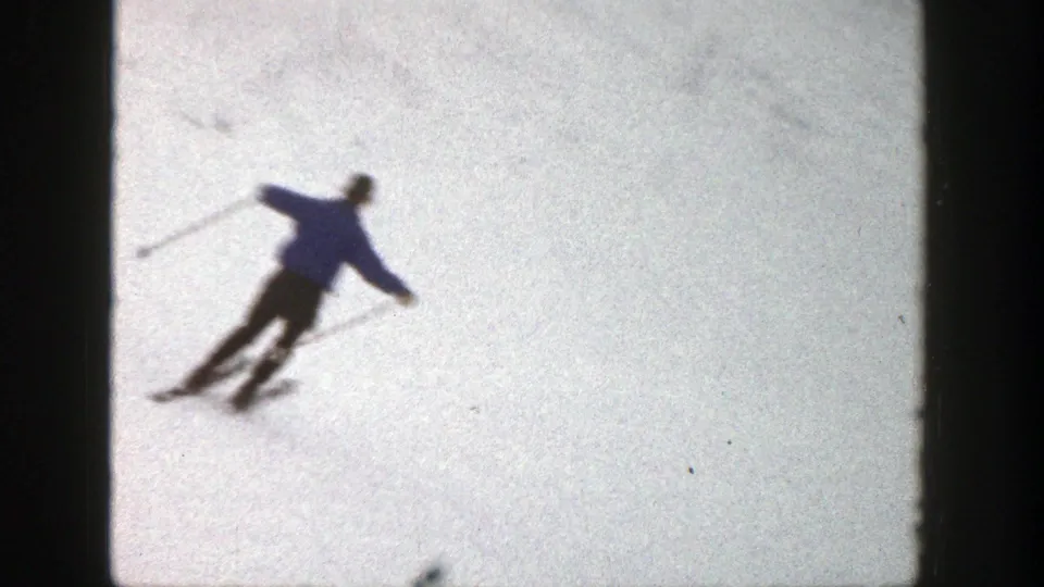 In Aspen, Colorado, 1961 footage, a skier in blue descends across snow while using poles for balance.