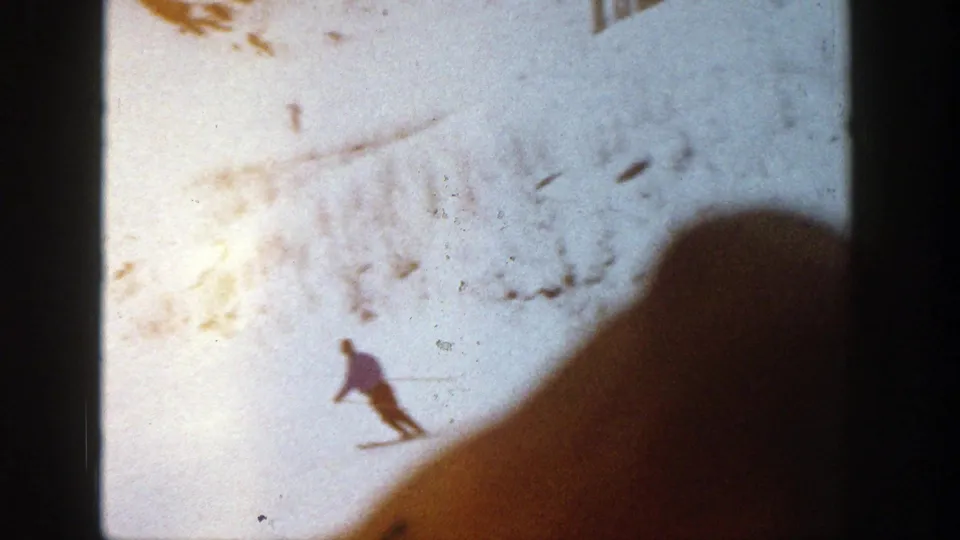 The skier becomes a small figure on the Aspen slope, with hillside texture and a dark foreground shape intruding into the 8mm frame.