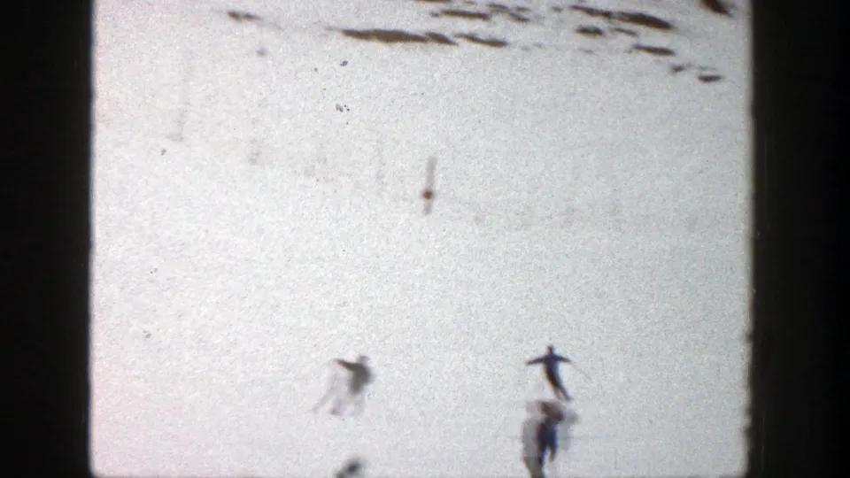 Distant skiers cross a bright Aspen snow slope in a soft, grainy 8mm frame from 1961.