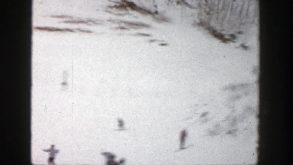 Distant skiers appear on a bright Aspen snowfield, with faint tracks and trees at the top of the 8mm frame.